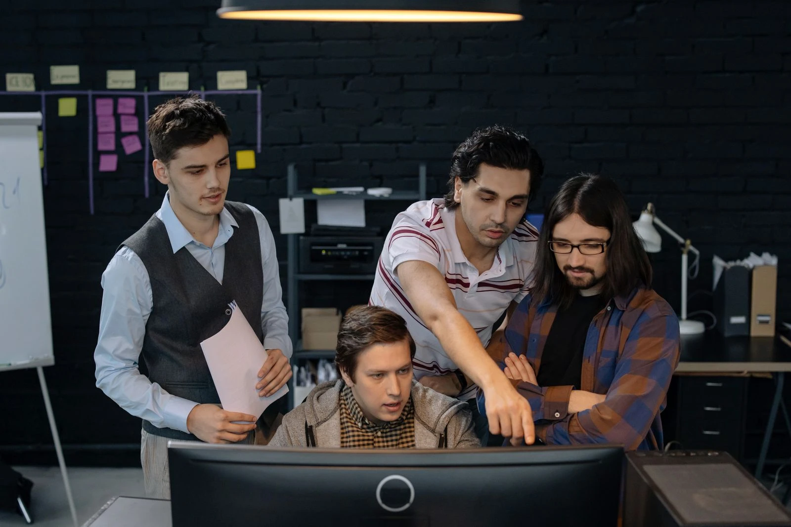 Four-person tech team reviewing work together at a screen