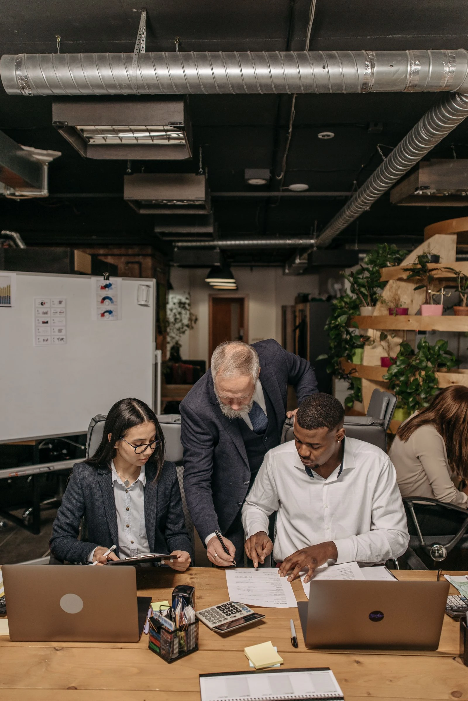 Senior consultant guiding two colleagues through work at their desks