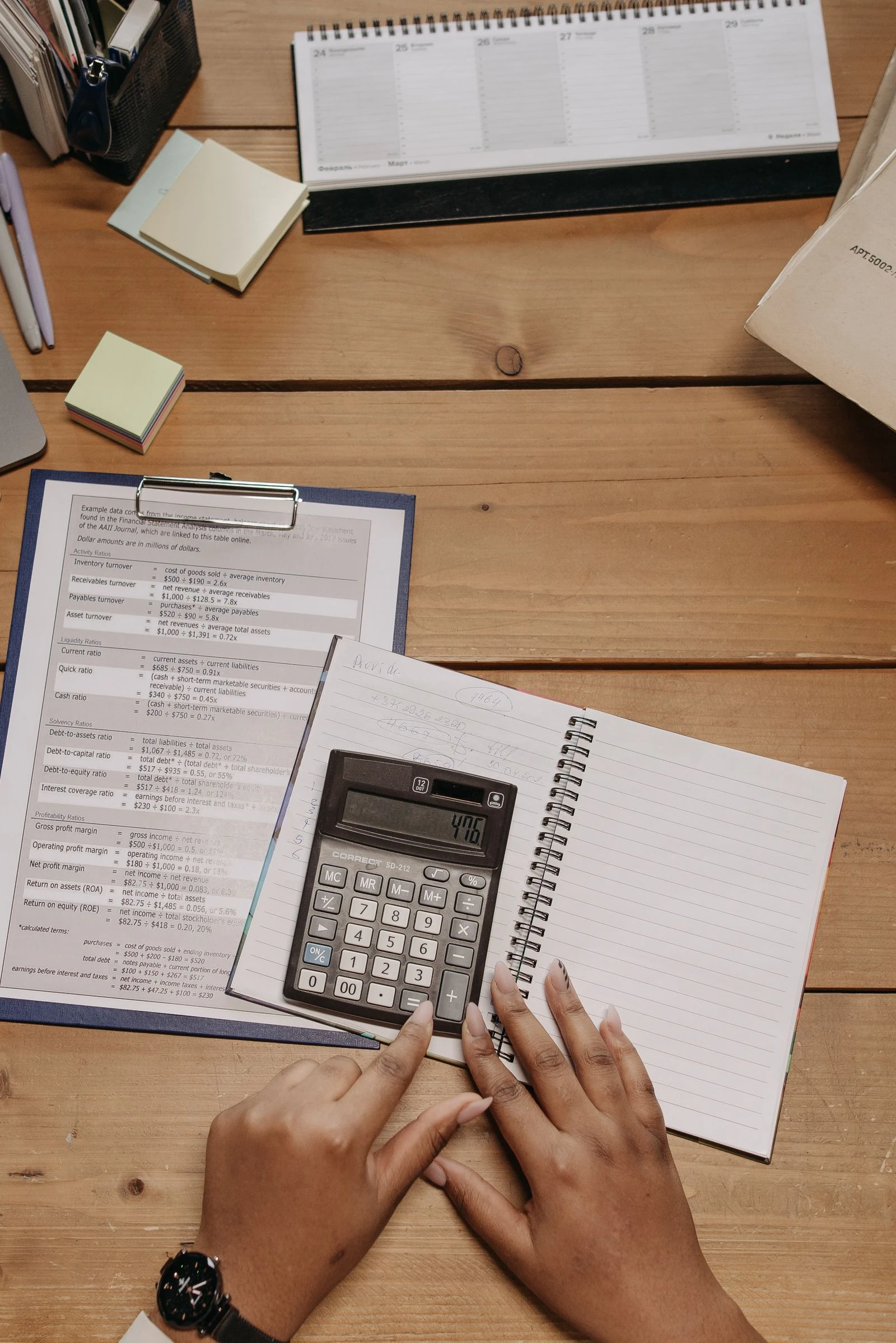 Hands with a calculator reviewing financial ratio worksheets