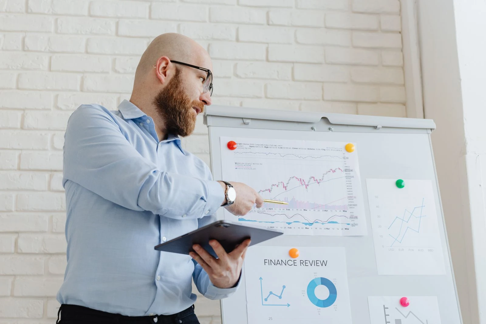 Presenter pointing at financial charts on a finance review board