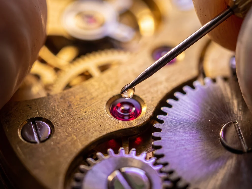 A fine oiler placing a single bead of oil on a ruby jewel bearing, a metaphor for ongoing optimisation and support