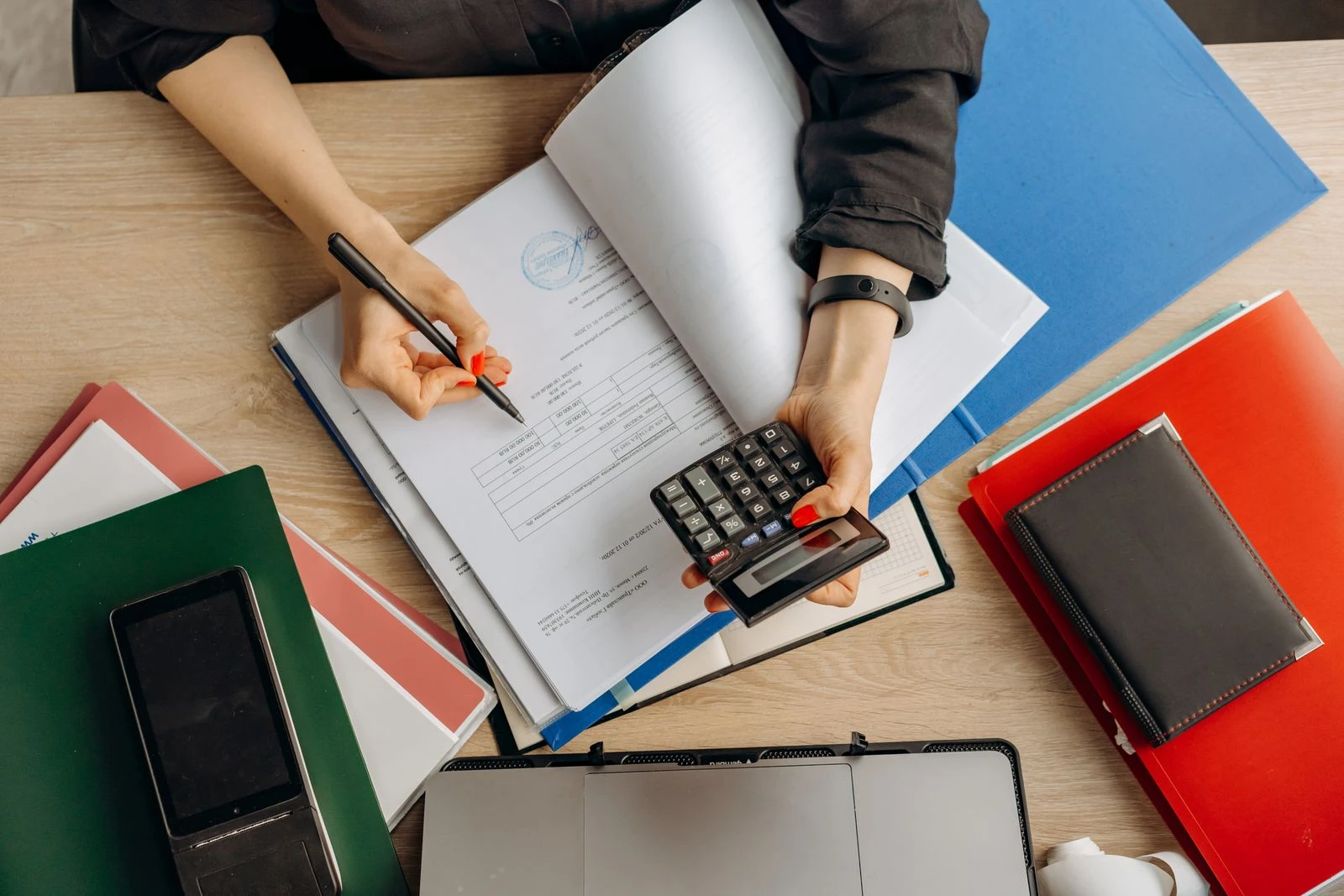 Overhead view of hands reviewing financial documents with a calculator