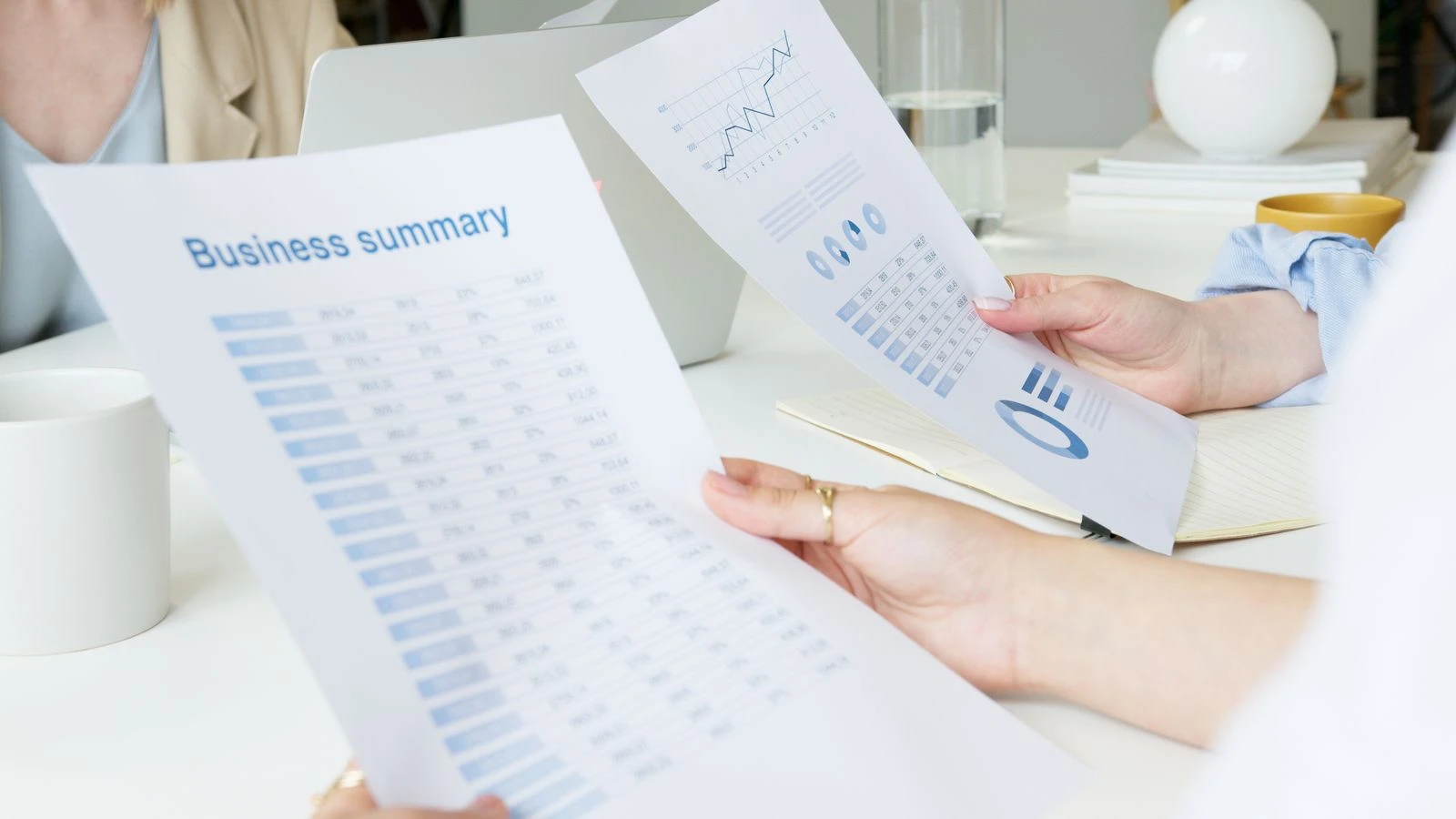 Two hands holding and comparing two separate report printouts