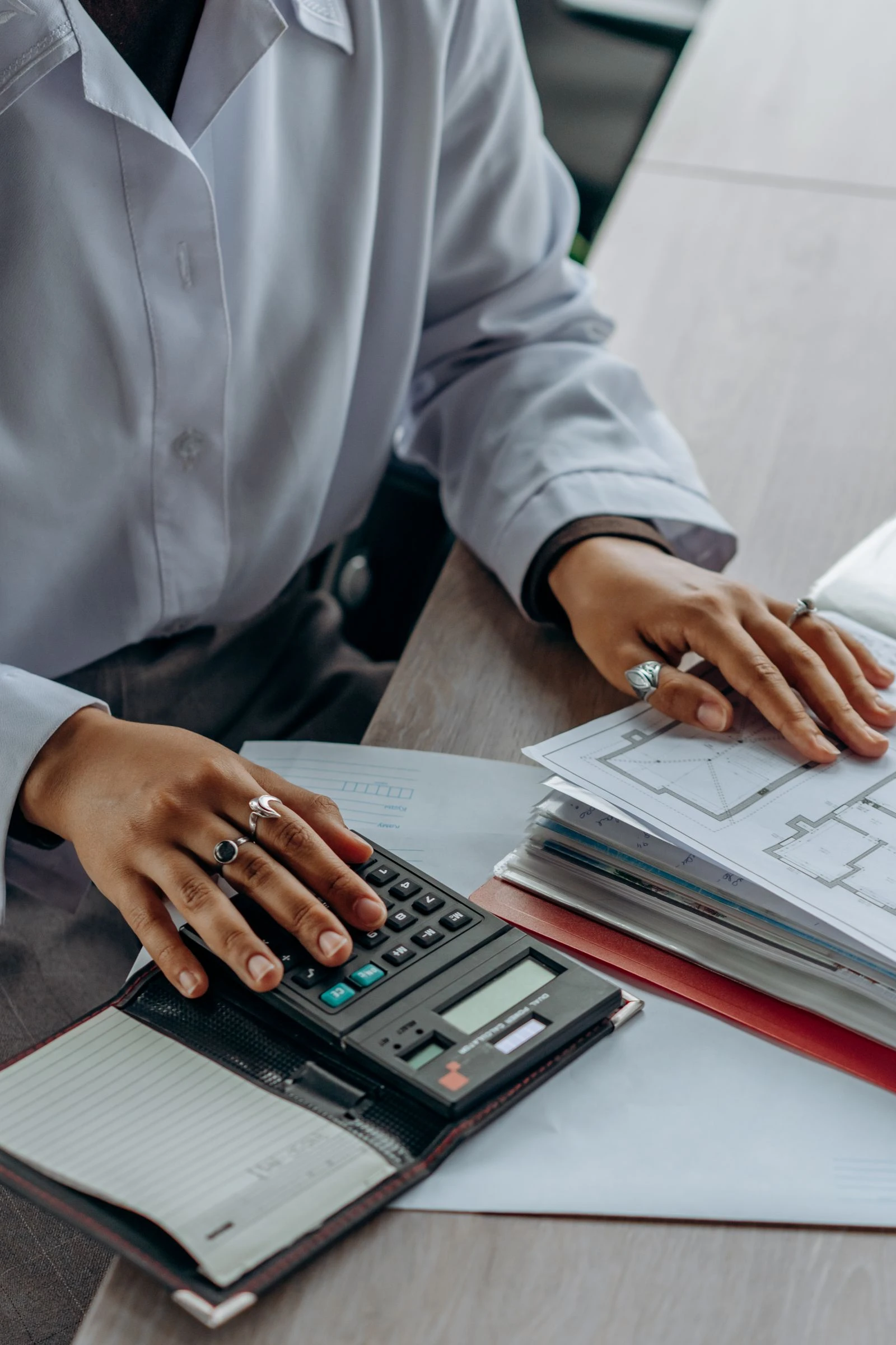 Hands with a calculator and documents posting entries at month-end
